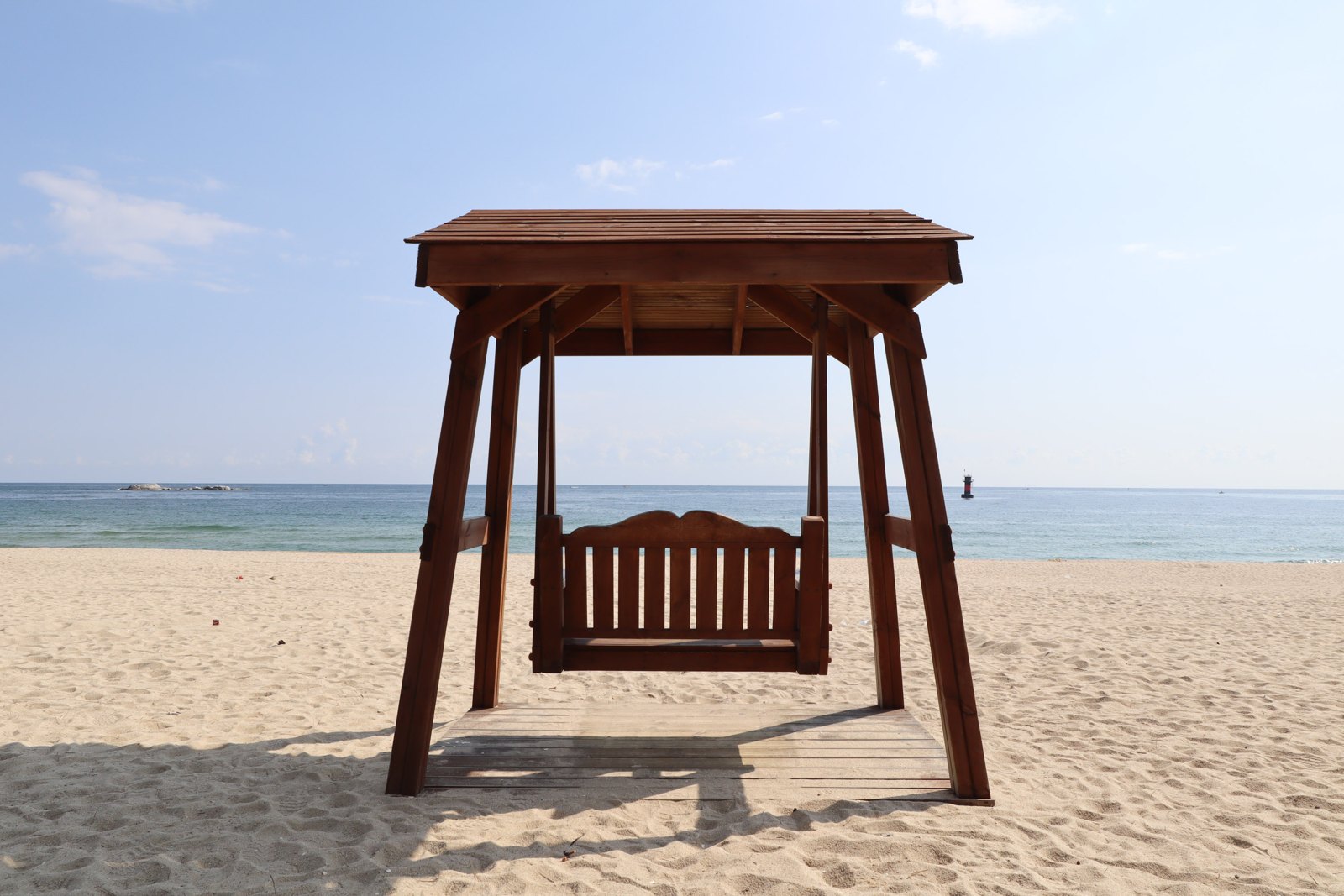 A wooden swing bench on the sand at Gyeongpo Beach, Gangneung, facing the East Sea