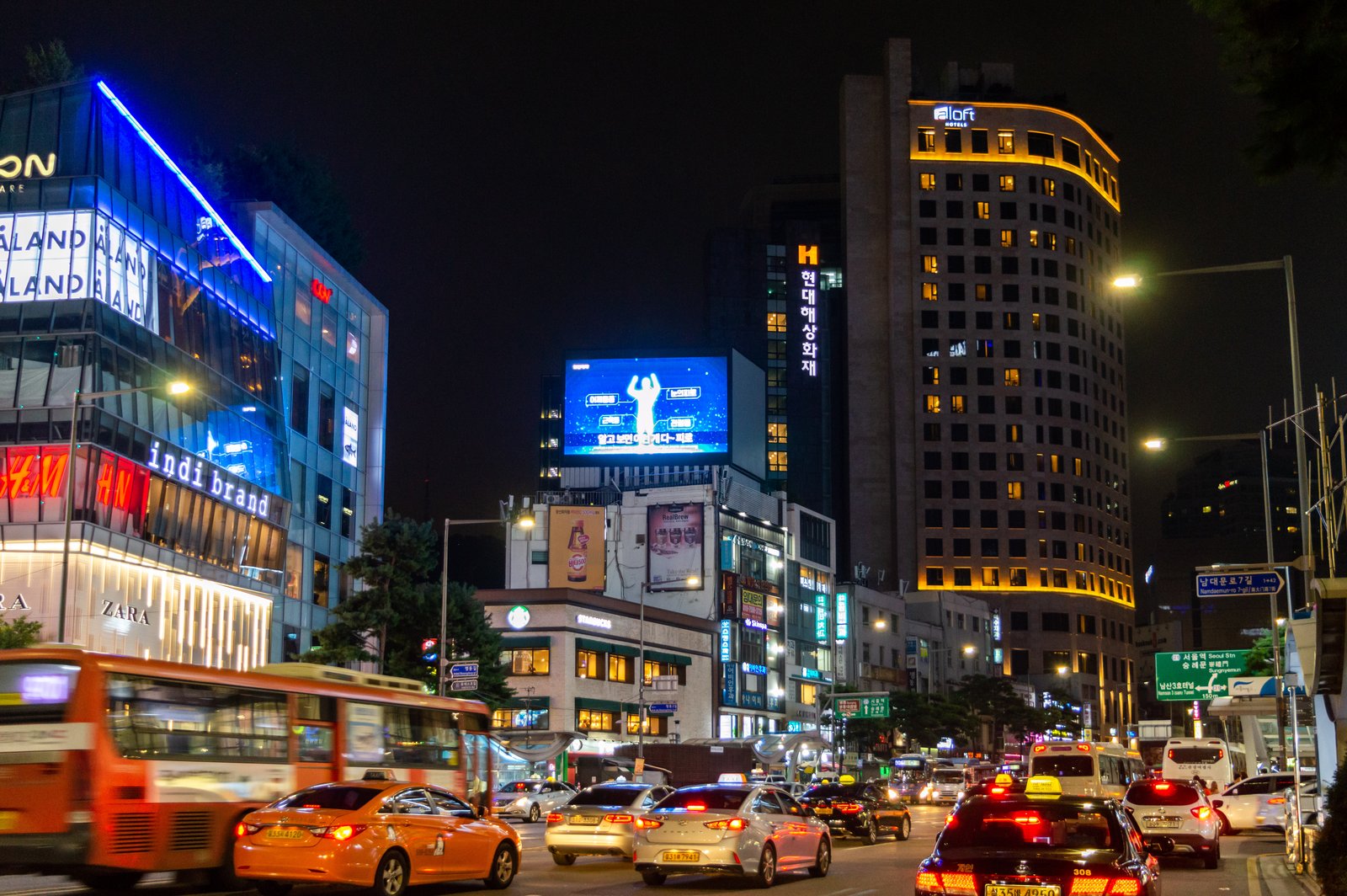 Namdaemun-ro street in Myeongdong at night with lit storefronts and traffic, Seoul