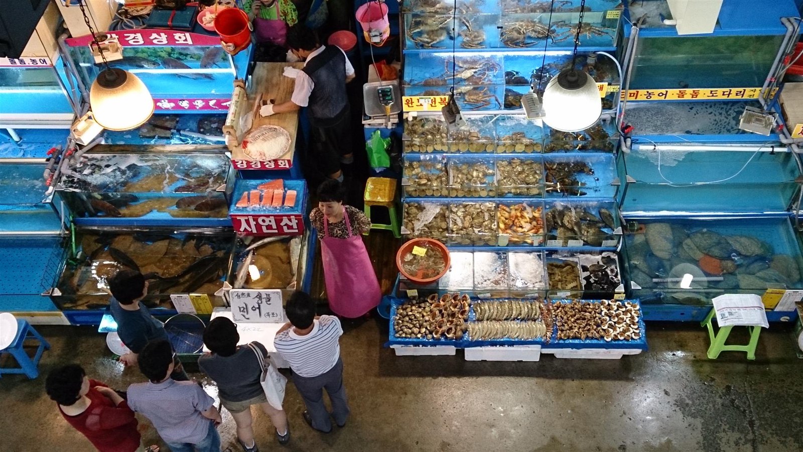 Customers at a Noryangjin fish market stall with tanks of live crab, shellfish and fish, seen from above (2013, former hall)